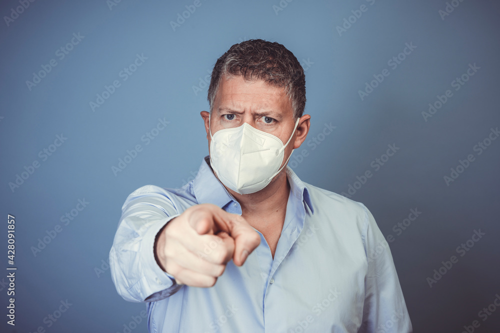 Middle-aged man with ffp2 protective mask and blue shirt in front of blue background during lockdown