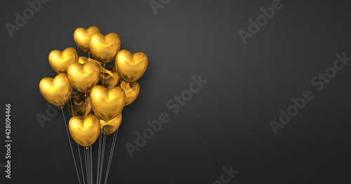 Gold heart shape balloons bunch on a black wall background. Horizontal banner.