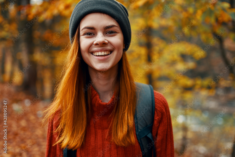 portrait of a beautiful woman in a hat sweater with a backpack on her back in the autumn forest in nature portrait of a beautiful woman in a hat sweater with a backpack on her back in the autumn forest in nature