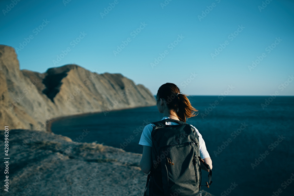 woman with backpack in the mountains in nature back view