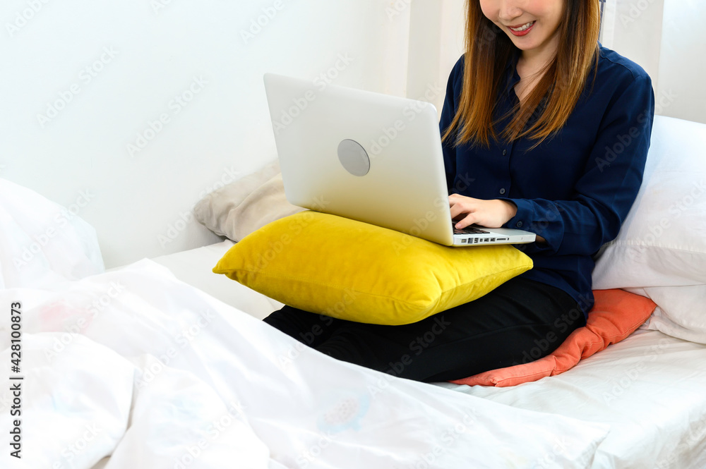 Asian women are happy and work with laptop computers in bed. Asian women are happy and work with laptop computers in bed.