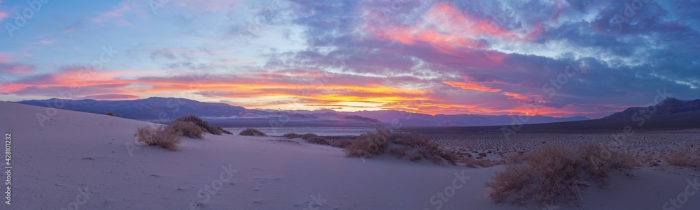 Eureka Dune at sunset is illuminated by a gentle pink light against a backdrop of dramatic clouds, Death Valley National Park, USA