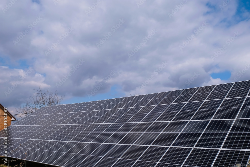Solar panels near a country house on a sunny day with tragic clouds. Copy space. Solar panels near a country house on a sunny day with tragic clouds. Copy space.
