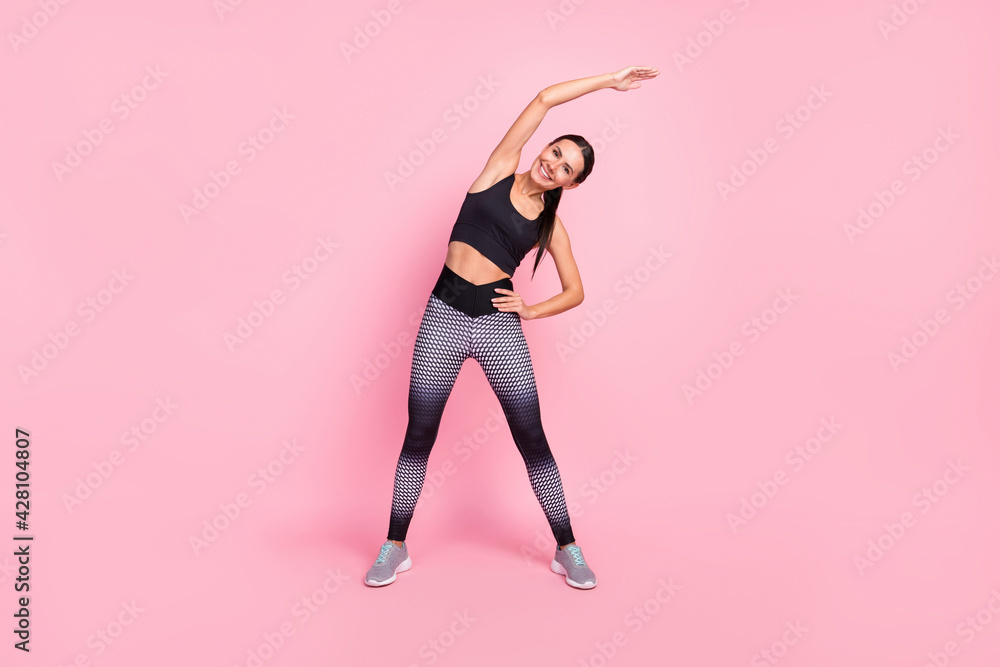 Full length photo of young woman raise hand hold waist warm-up gymnastics isolated on pink color background Full length photo of young woman raise hand hold waist warm-up gymnastics isolated on pink color background