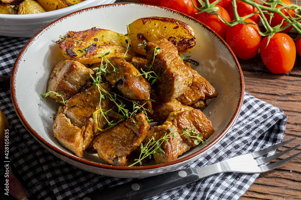 Appetizing stew of pork tenderloin meat cooked in the wok, cut into cubes. With roasted and golden potatoes, garlic, salt, oregano and fresh tomatoes. Homemade look. Close-up Appetizing stew of pork tenderloin meat cooked in the wok, cut into cubes. With roasted and golden potatoes, garlic, salt, oregano and fresh tomatoes. Homemade look. Close-up