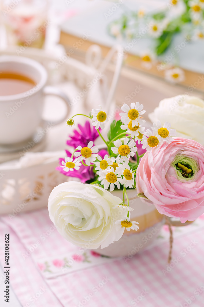 Beautiful tender blossoming of fresh cut bouquet with cup of tea nad books in background Beautiful tender blossoming of fresh cut bouquet with cup of tea nad books in background