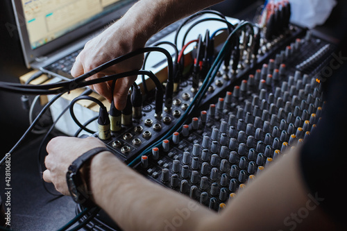 Sound engineer plugging jack audio cable on studio mixer.