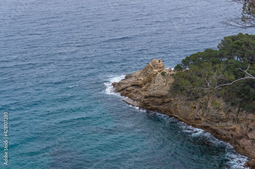 People fishing on some rocks in a cove with a cloudy day