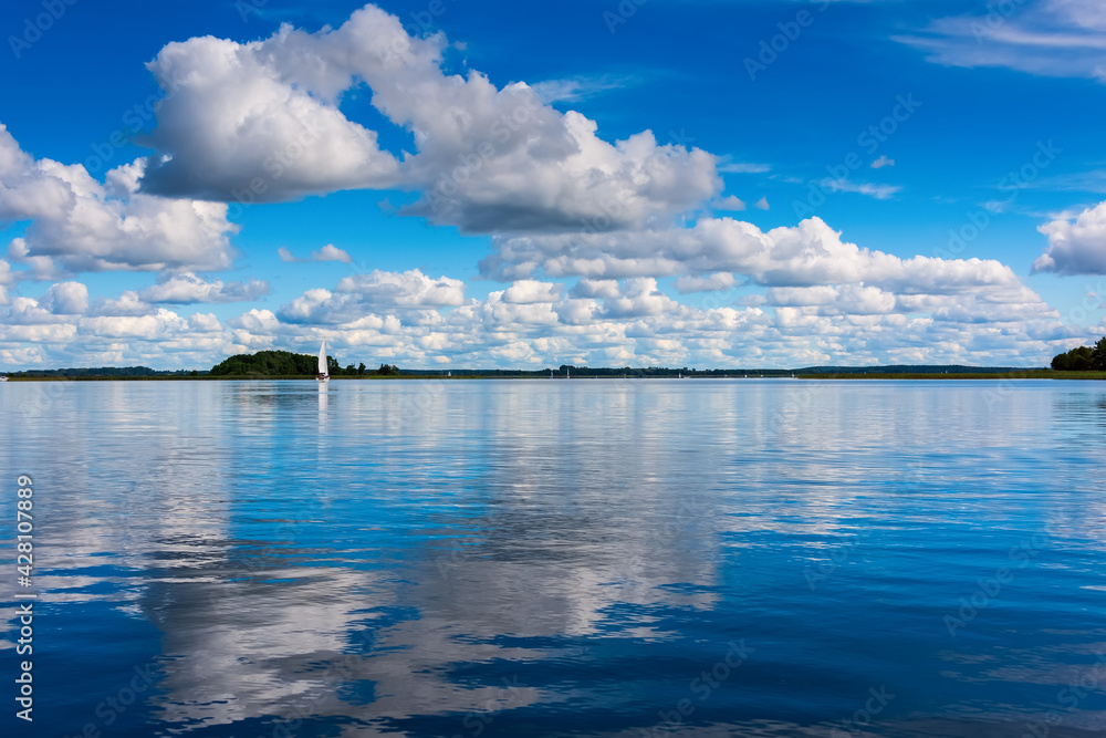 beautiful reflections of a white clouds and blue sky on lake water surface. Summer vacations
