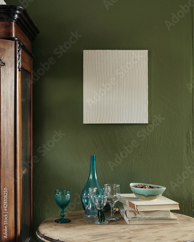 Modern french interior. Old closet, old table, books and glasses. Modern painting on a dark green background