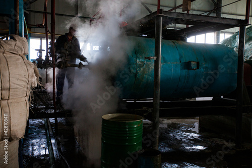 Factory workshop and glass recycling equipment.Worker in steam cloud. Glass production. Ferrum Vtor company. Shymkent, Kazakhstan.  photo