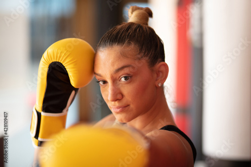 Boxer woman in boxing gloves. Focus is on background. © liderina