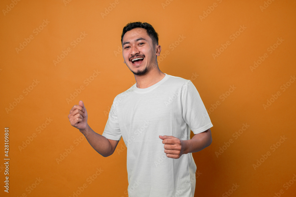 Portrait of lucky, attractive, excited, glad man with wide open mouth and raised arms looking at camera celebrating successfully passed exams, completed work, isolated on yellow background Portrait of lucky, attractive, excited, glad man with wide open mouth and raised arms looking at camera celebrating successfully passed exams, completed work, isolated on yellow background