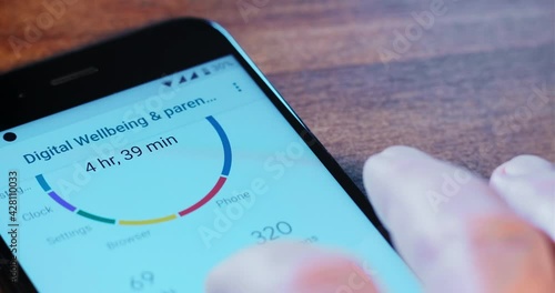 Person uses digital wellbeing and parental control app of modern mobile phone with white screen on wooden table close view