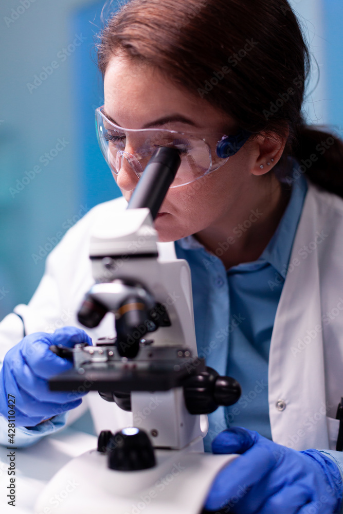 Medical scientist analyzing a test with microscope for pharmaceutical expertise. Modern laboratory with research equipment for virus study and vaccine science development. Medical scientist analyzing a test with microscope for pharmaceutical expertise. Modern laboratory with research equipment for virus study and vaccine science development.