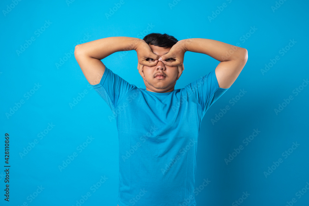 young man acting silly on blue background young man acting silly on blue background