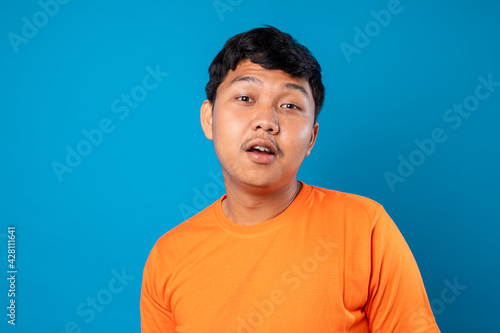 Portrait of Asian man with laugh face. Isolated on blue background. © Danykur