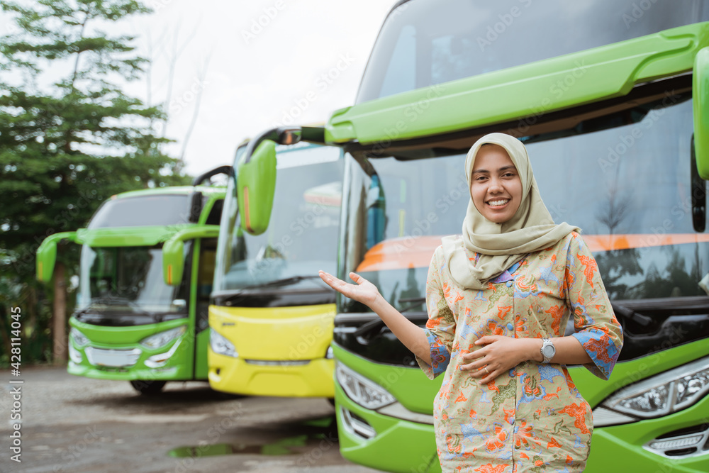 a veiled female bus crew smiling with hand gestures offering something against the background of the bus fleet a veiled female bus crew smiling with hand gestures offering something against the background of the bus fleet