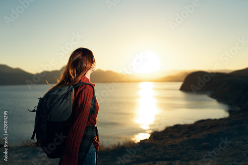 woman tourist with backpack on nature landscape sunset