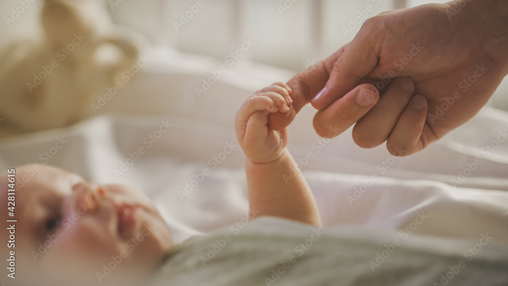 Close Up Shot of Newborn Baby Playing With Mother's Hand and Finger while Lying on the Back in Child Crib. Caucasian Neonate Toddler Bodning with Mom. Concept of Childhood, New Llife and Parenthood Close Up Shot of Newborn Baby Playing With Mother's Hand and Finger while Lying on the Back in Child Crib. Caucasian Neonate Toddler Bodning with Mom. Concept of Childhood, New Llife and Parenthood