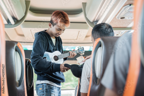 a passenger gives money to a busker wearing an ukulele while on the bus