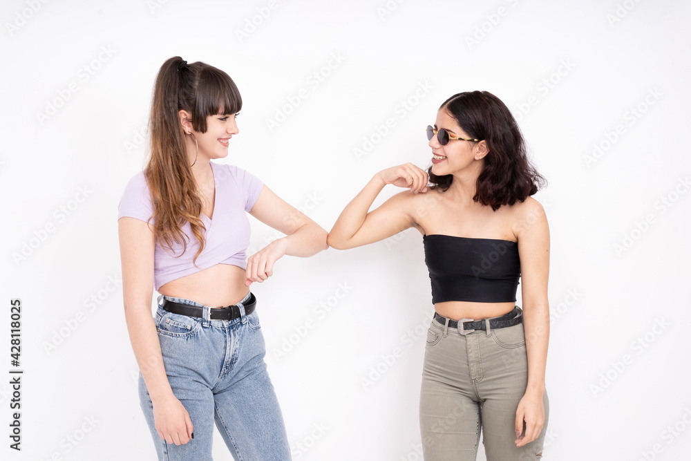 Two female friends greeting each other with elbows on white background Two female friends greeting each other with elbows on white background
