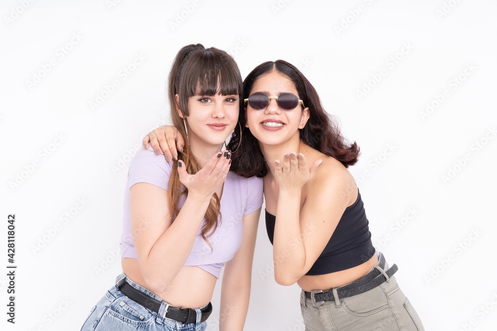 Two girlfriends blowing a kiss at the camera having fun on white background Two girlfriends blowing a kiss at the camera having fun on white background