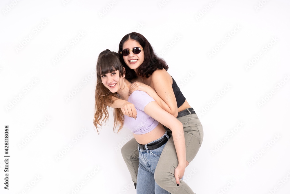 Two girlfriends playing on top of each other smiling at camera having fun on white background Two girlfriends playing on top of each other smiling at camera having fun on white background
