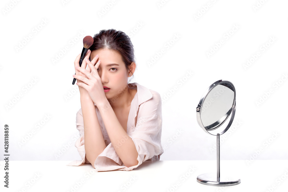 Portrait of beautiful charming young Asian woman posing facial with cosmetic and sitting with white table, beauty of female face with skincare on white background, healthcare and skin care concept. Portrait of beautiful charming young Asian woman posing facial with cosmetic and sitting with white table, beauty of female face with skincare on white background, healthcare and skin care concept.