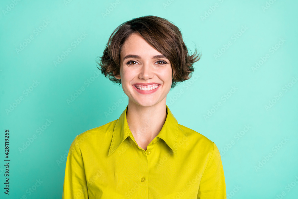 Photo portrait of smiling short haired girl in green shirt isolated on vivid teal color background Photo portrait of smiling short haired girl in green shirt isolated on vivid teal color background