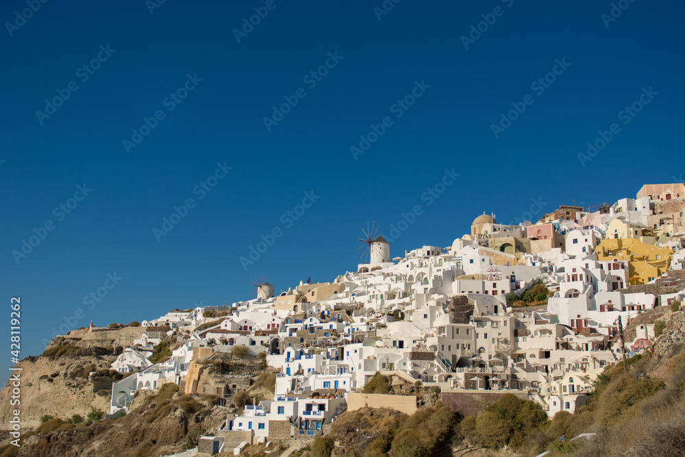 Beautiful view of the famous Santorini windmills and white buildings on the cliff