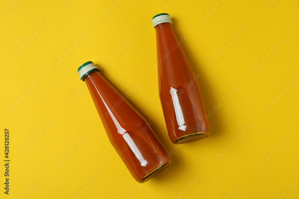 Bottles of carrot juice on yellow background Bottles of carrot juice on yellow background
