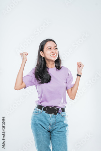 Asian young girl smiling happy while clenched into fists and raised two hands isolated on a white background
