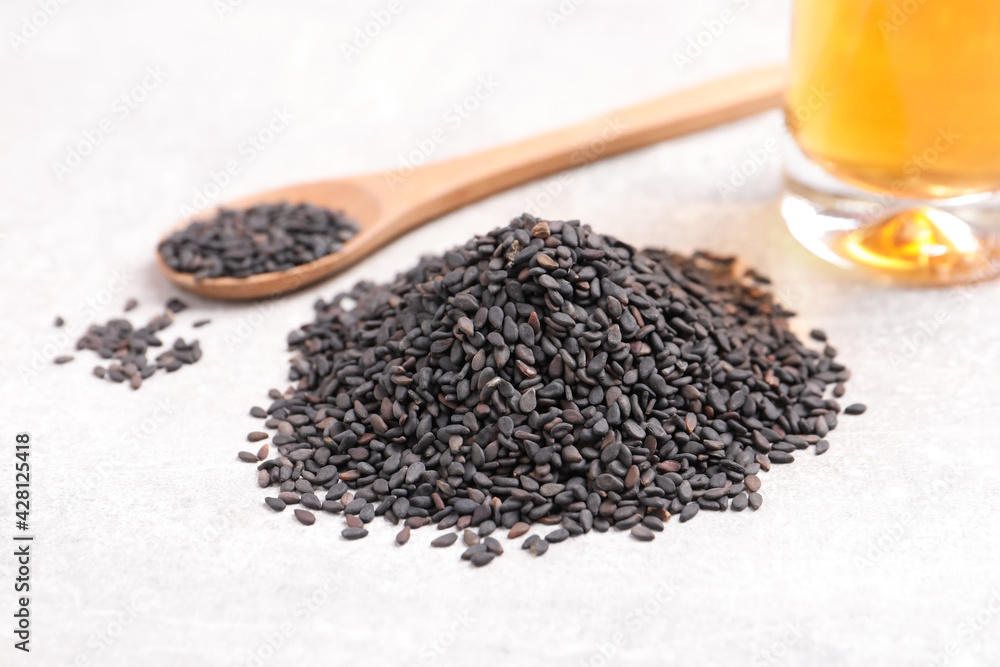 Black sesame seeds and oil on light table, closeup Black sesame seeds and oil on light table, closeup