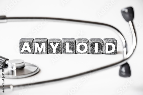 Stone block form word AMYLOID with stethoscope. White background. Medical concept. protein, collects in tissues when diseases, Alzheimer's disease