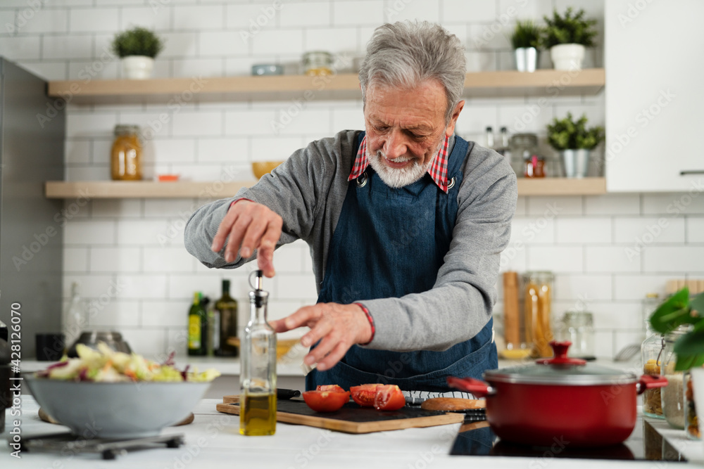 Senior man in kitchen. Happy smiling man cooking delicious food.. Senior man in kitchen. Happy smiling man cooking delicious food..