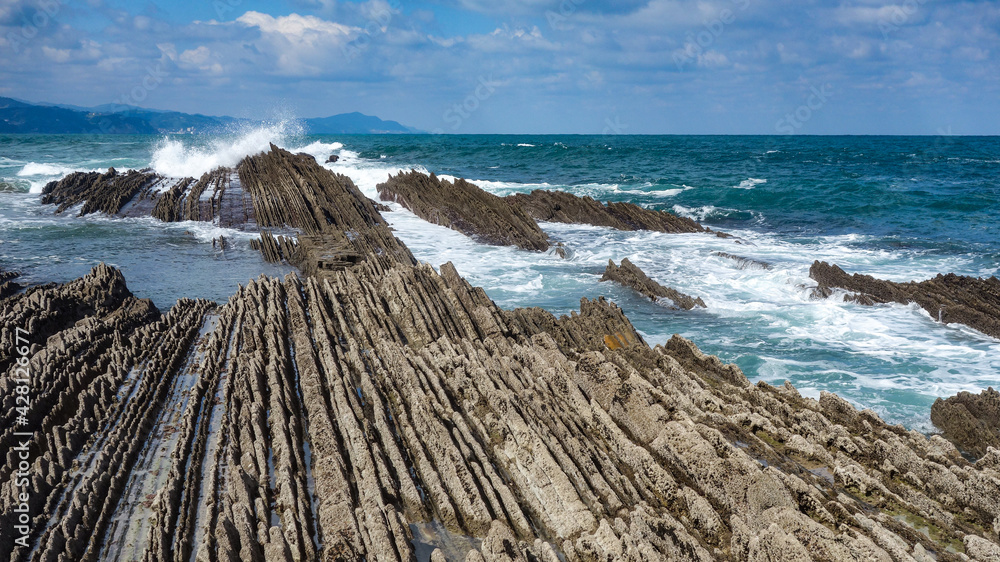 Fototapeta premium Zumaia, Spain - March 17, 2021: Flysch rock formations on the beach in Zumaia, Basque Country, Spain