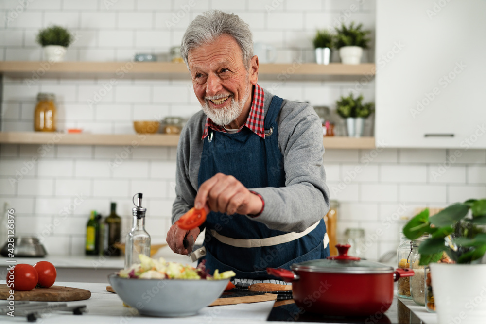 Senior man in kitchen. Happy smiling man cooking delicious food.. Senior man in kitchen. Happy smiling man cooking delicious food..