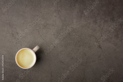 Top view of a cup of hot espresso black coffee with brown espresso coffee foam crema on the top in a white grey pastel ceramic coffee mug put on corner grunge look dark color cement table background.