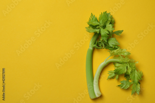 Fresh green сelery on yellow background, space for text © Atlas