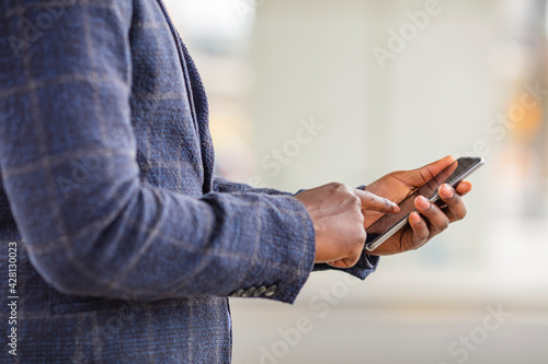 Closeup shot of an unrecognizable businessman using a cellphone in the city. Staying connected in this digital age. Cropped shot of an unrecognizable businessman standing alone 