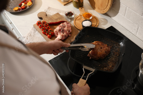 Man taking cooked meat from frying pan, above view