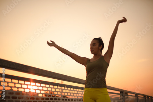 Life is beautiful. African sports woman standing on the bridge and stretching her arms.