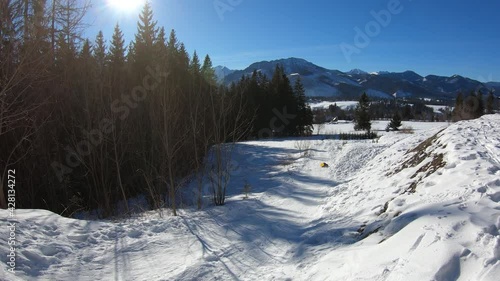 Time lapse of family sledding through the hill during winter sunny day with clear sky in Zakopane, Poland. Tatry mountains in the background.