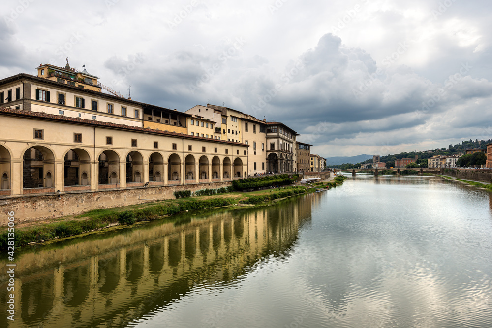Florence. Arno River view from the Medieval Ponte Vecchio (Old Bridge). On the left the Vasari Corridor (Corridoio Vasariano, 1565), which connects Palazzo Vecchio with Palazzo Pitti. Tuscany Italy.