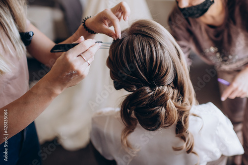 gathering of the bride, hands of the hairdresser and the bride's hairstyle close-up