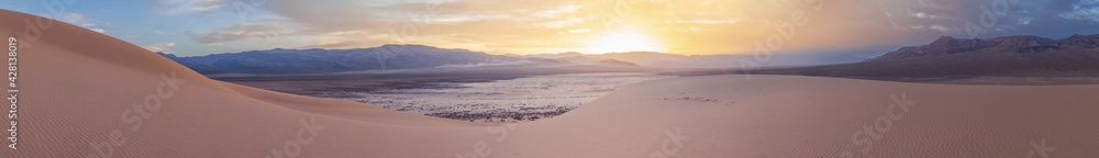 Eureka Dune at sunset is illuminated by a gentle pink light against a backdrop of dramatic clouds, Death Valley National Park, USA