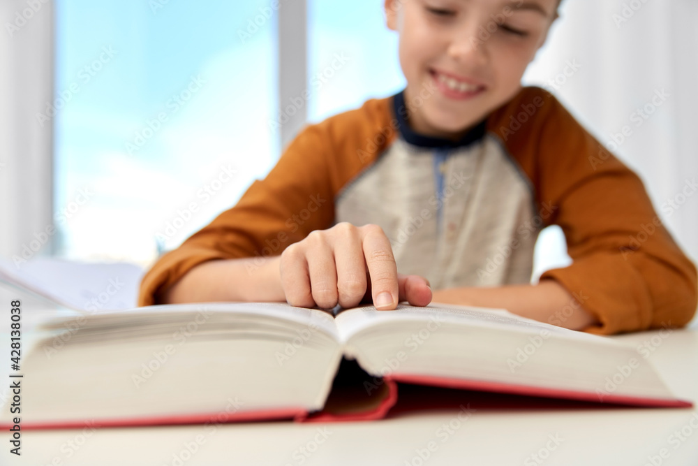 education, childhood, people, homework and school concept - smiling student boy with book writing to notebook at home education, childhood, people, homework and school concept - smiling student boy with book writing to notebook at home