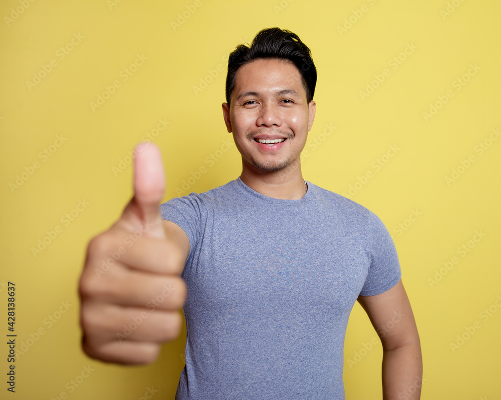 handsome man smile expression give sign thumbs isolated on a yellow color background handsome man smile expression give sign thumbs isolated on a yellow color background