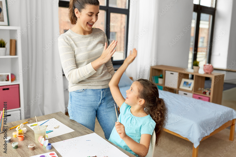 family, motherhood and leisure concept - mother spending time with her little daughter drawing with colors and making high five gesture at home family, motherhood and leisure concept - mother spending time with her little daughter drawing with colors and making high five gesture at home